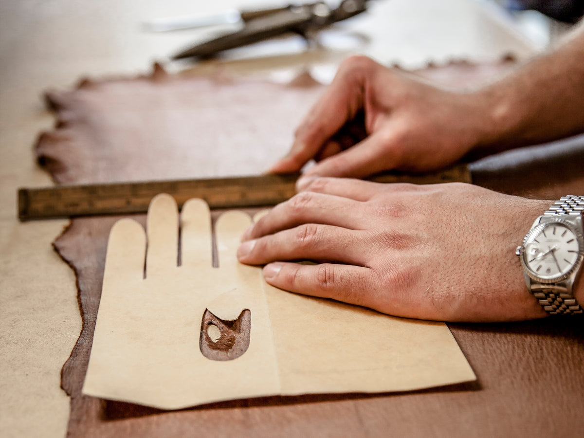 Hands measuring palm circumference with a tape measure to find the right glove size