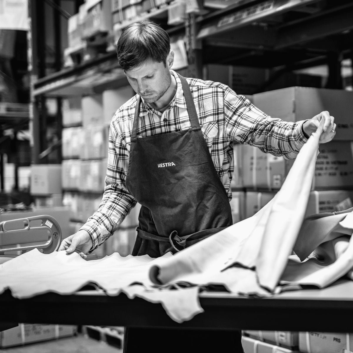 Craftsman in a Hestra apron sorting leather hides in our factory warehouse